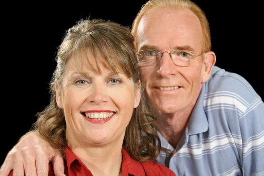 Happy middle aged couple smiling and looking to camera.