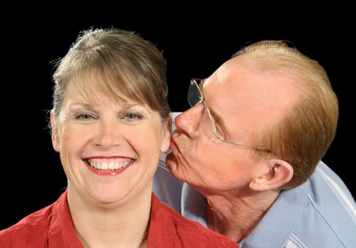 Middle aged husband gives his wife a peck on the ear.