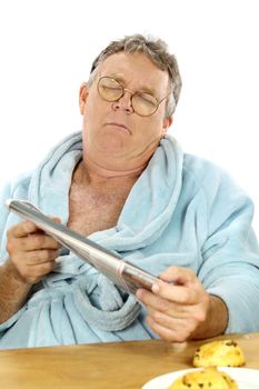 Middle aged man in a bath robe struggles to read the morning paper.
