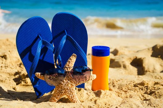 Blue Flip flops, sunscreen and starfish with sunglasses on sandy beach in Hawaii, Kauai