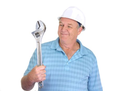 Middle aged construction worker smiles looking at a large wrench.