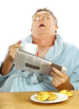 Nerdy middle aged man falls asleep at the breakfast table with a cup of tea and muffins.