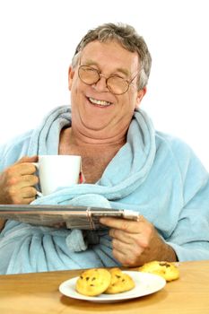 Nerdy middle aged man smiling while having breakfast and reading the paper.