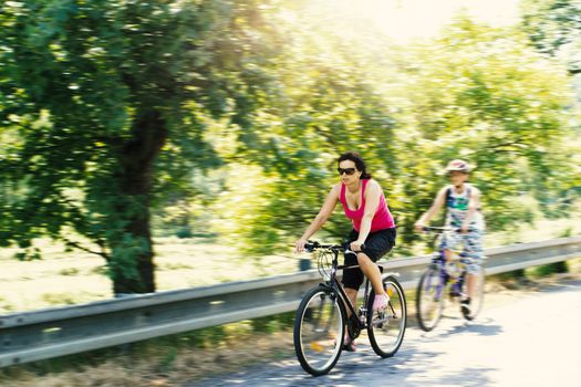 Mother with sons riding bicycle on trip in sunny day with motion blur