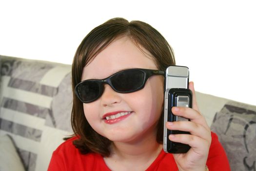 Little girl with sunglasses holds up her cell phone.