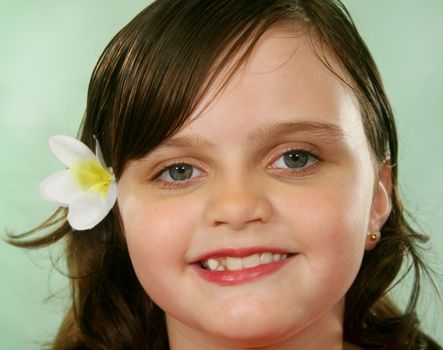 Happy and contented little girl with a frangipani in her hair.