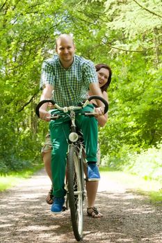 Happy young couple is taking a ride on a bicicle