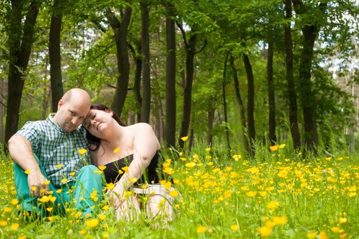 Happy young couple is sitting in a field of buttercups
