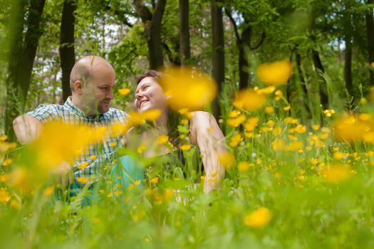 Happy young couple is sitting in a field of buttercups