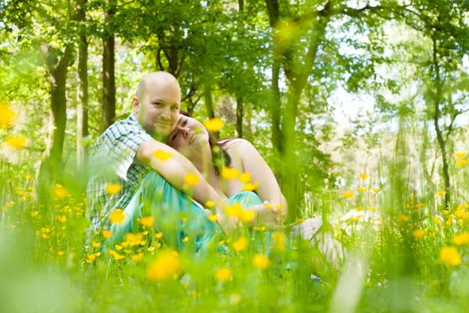 Happy young couple is sitting in a field of buttercups