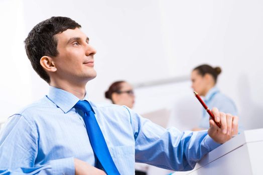 Portrait of a businessman in a blue shirt in the background of colleagues discussing