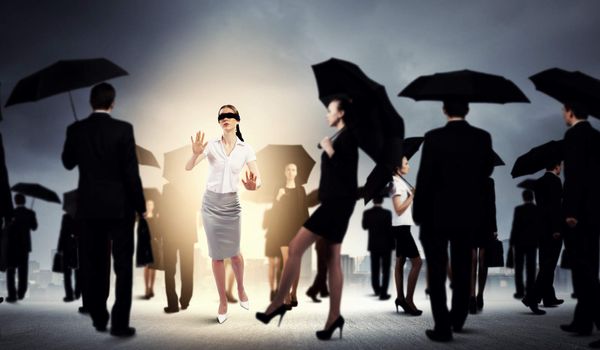 Image of businesswoman in blindfold walking among group of people