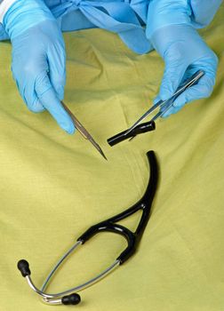 A surgeon dissects a stethoscope in order to cut costs.