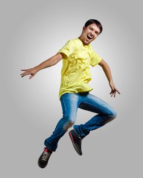 Modern slim hip-hop style man jumping dancing on a grey background