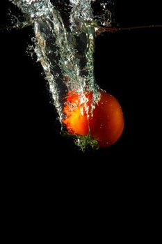 fresh tomato uder water on black background