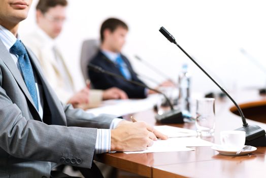 Businessman writing on paper notes, to communicate with colleagues in the background