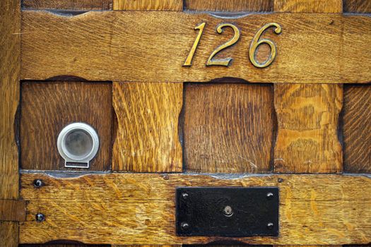 Part of wooden front door with number 123 and eyelet.