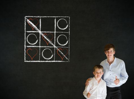 Thumbs up boy dressed up as business man with teacher man and chalk tic tac toe love valentine concept on blackboard background