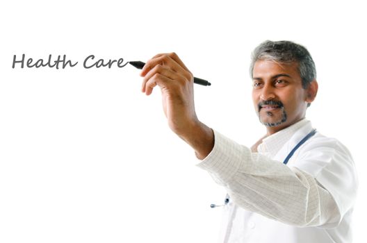 Health care concept. Mature Indian male medical doctor writing on blank space, standing isolated on white background. Handsome Indian model portrait.