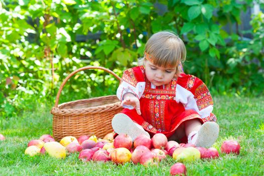 little girl in the Russian national dress with a basket of apples