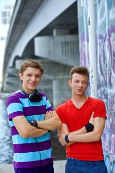 Portrait of happy two teens boys by painted wall looking at camera. Vertical view