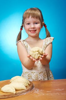 Smiling little girl kneading dough at kitchen with baking a pie