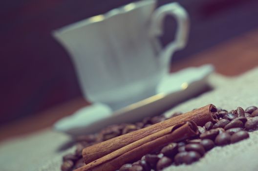 Coffee cup with cinnamon and coffee beans background