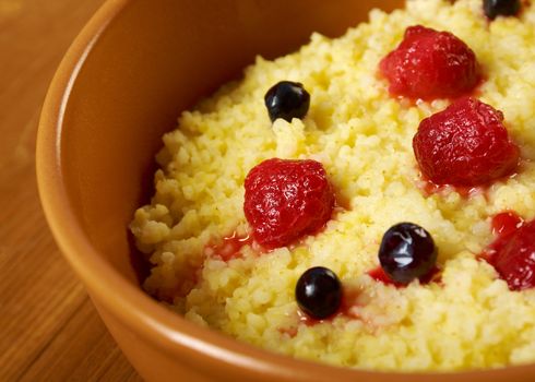 Millet porridge with berry in brown bowl on table