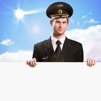 pilot in the form of holding an empty billboard on the background of sky with clouds, place for text