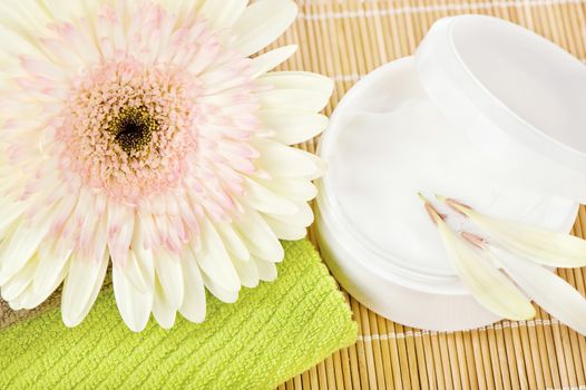 Beautiful flower on top of green towel with skin care product