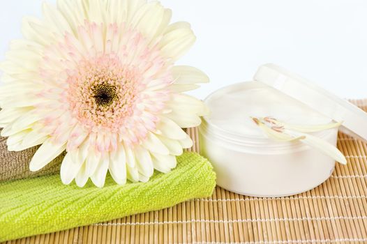 Ready to use skin care product, fresh flower on top of two towels and skin care product