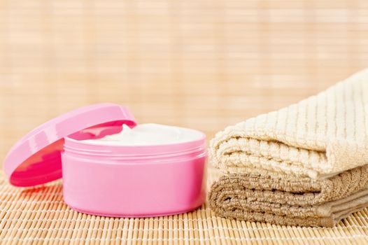 Hand cream in pink cup with two towels