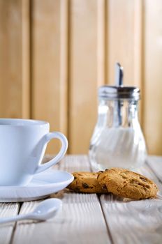 cup with cookies and sugar dispenser on table