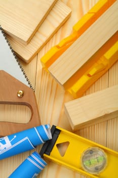 somposition of saw, timber, blueprints, level on wooden boards