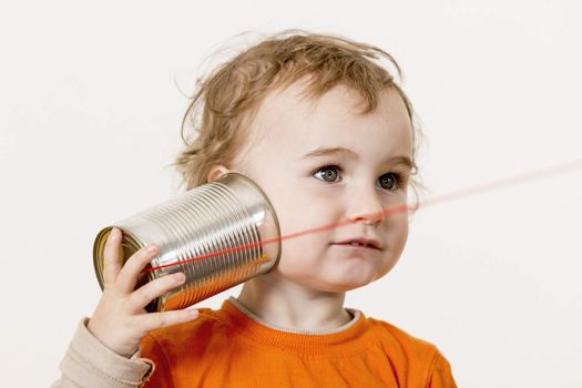 young child listening big to tin can phone. horizontal image with neutral light grey background
