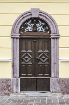 Old wooden house entrance with stone arch.