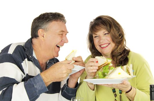Middle aged couple laughing and enjoying lunch together.
