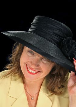 Middle aged woman looks out from under a black hat.