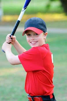 Portrait of little league baseball boy holding bat.