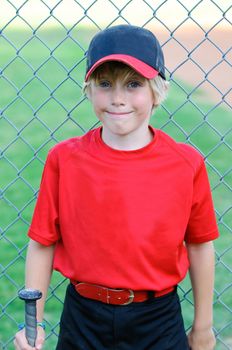 Portrait of baseball boy leaning on fence.