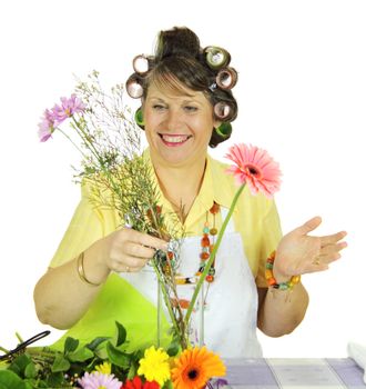 Middle aged frumpy housewife arranges flowers in a vase.