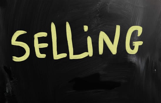 "Selling" handwritten with white chalk on a blackboard