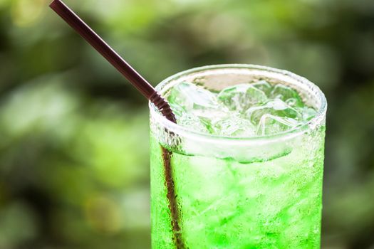 Glass of iced green drink with straw