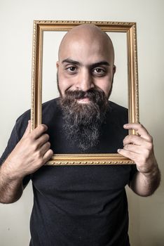 funny bearded man with golden frame on gray background