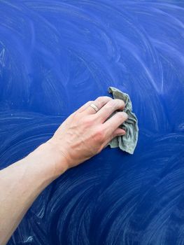 Person working on polishing a blue car