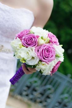 Elegant hand-tied bouquet of flowers in the hand of a bride