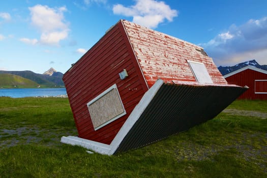 Red wooden hut turned around by heavy storm on Lofoten islands in Norway