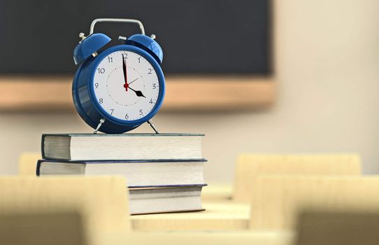 Alarm clock over a pile of books in a classroom