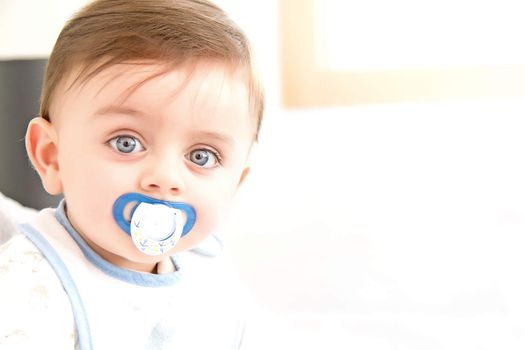 Cute baby with pacifier looking at the camera
