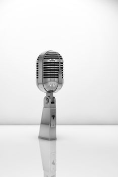 Vintage microphone on white reflective surface
